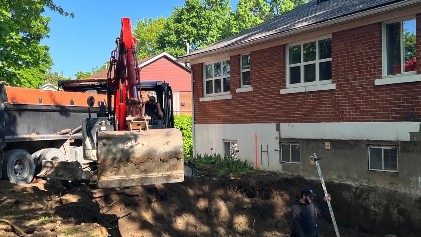Excavation de la fondation d’un agrandissement derrière un bungalow en brique