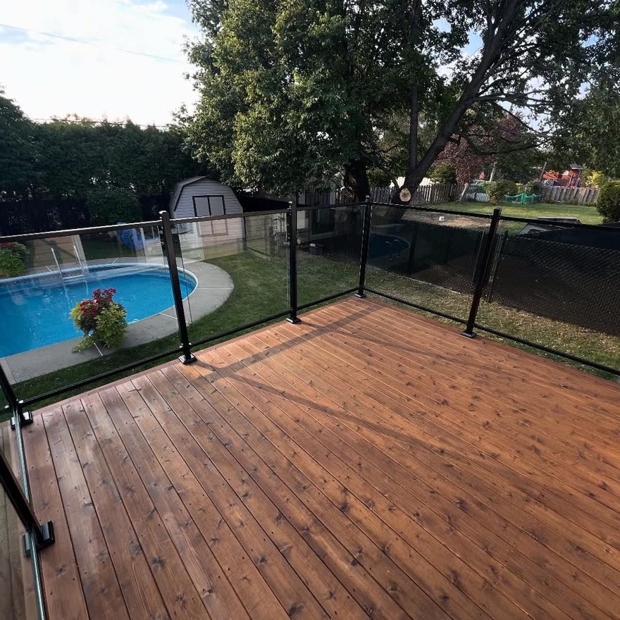 Terrasse en cèdre avec garde-corps en verre et clôture de piscine noire