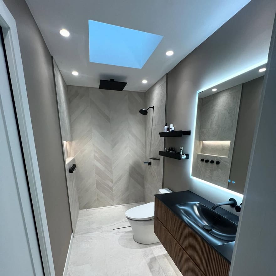 Douche à l’italienne en chevrons avec puits de lumière et robinetterie noire