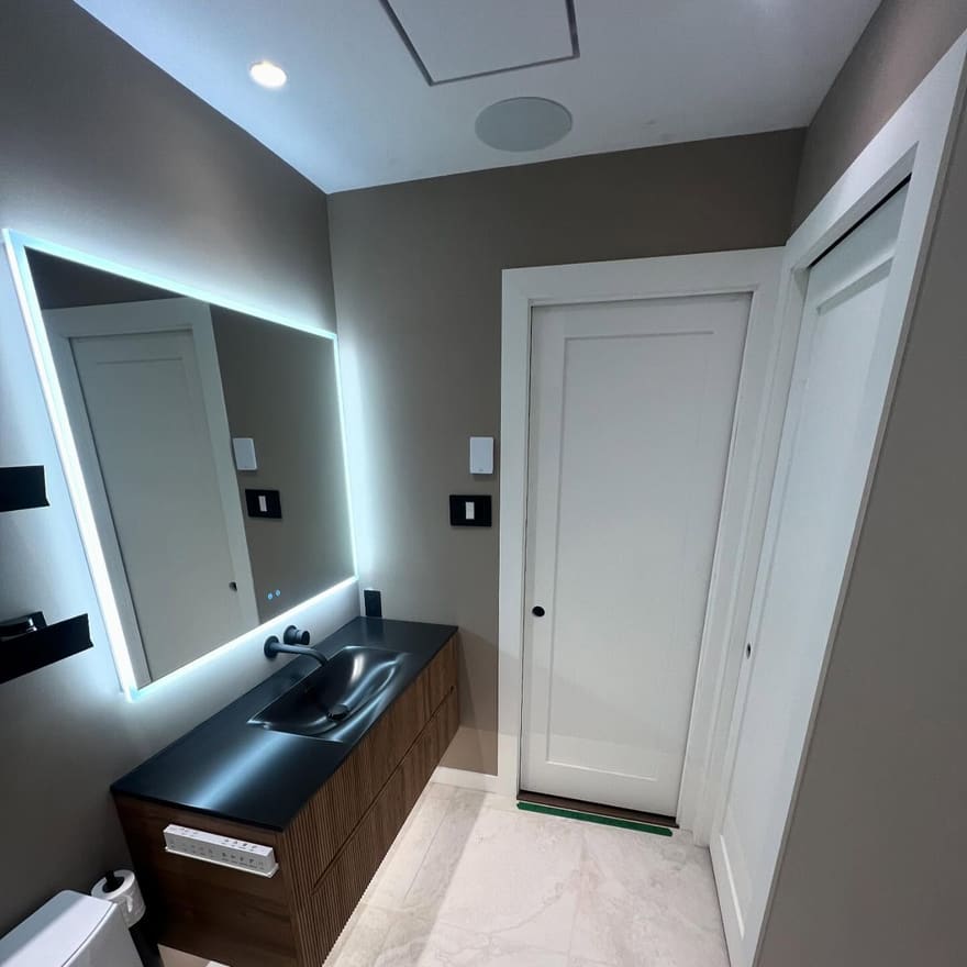 Salle de bain rénovée : vanité flottante en noyer, lavabo noir et miroir rétroéclairé